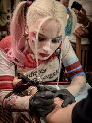 最重要的是，紋身師你可選擇小丑女Margot Robbie（真是小丑女裝咁幫你紋），或者Will Smith 操刀，或者超模 Cara Delevingne……呢間紋身店，如果開一定大排長龍，有得做！（ Margot 正為導演David Ayer 刺上 SKWAD。）