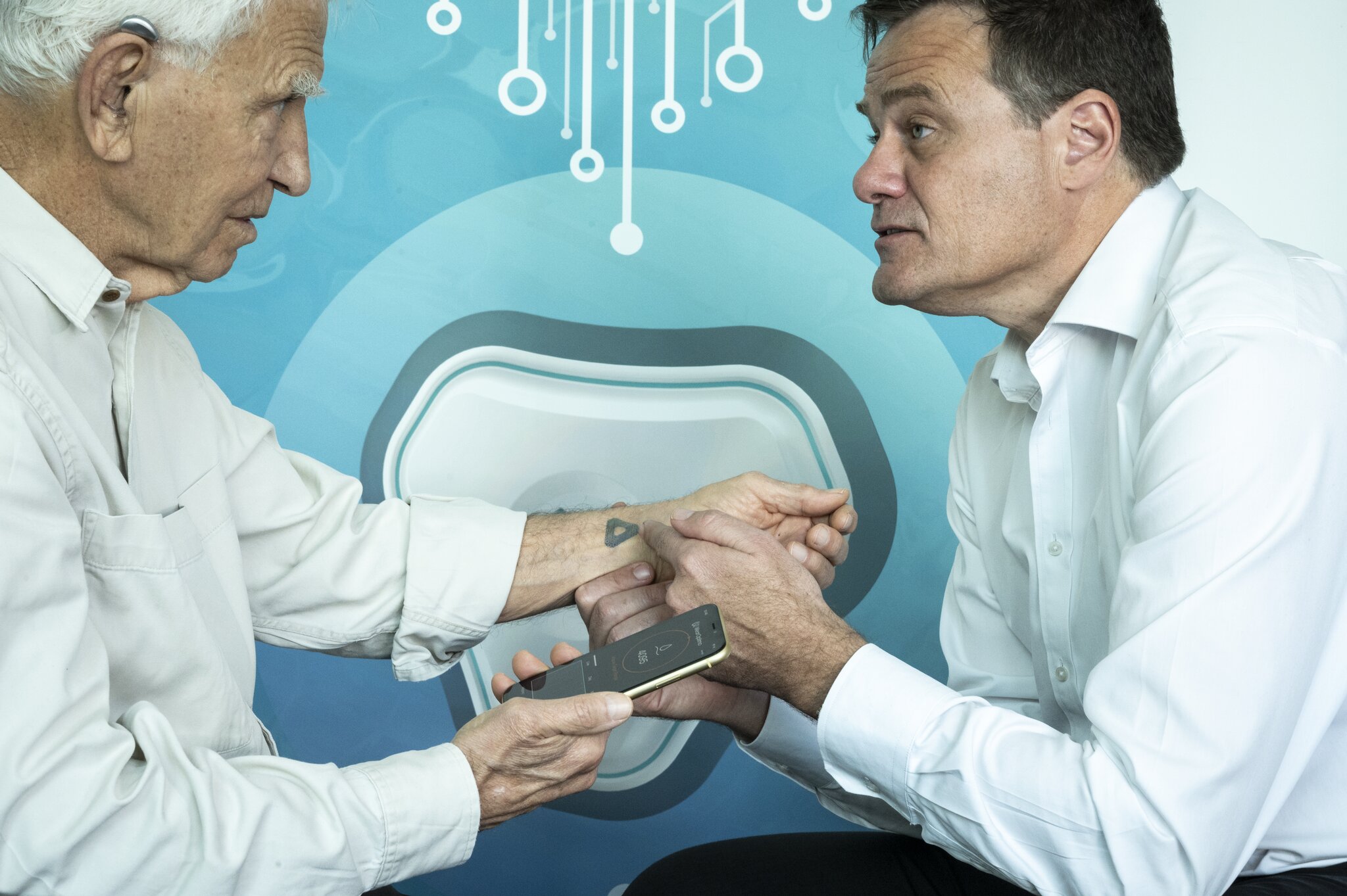 Mark Kendall教授(右)於長者的皮膚上測試微型貼片,此貼片不會對皮膚造成損傷,能讀取關鍵生氣資訊;如成功研發的話,此貼片便有機會實現個人化醫療。PHOTO / ©Rolex/Franck Gazzola