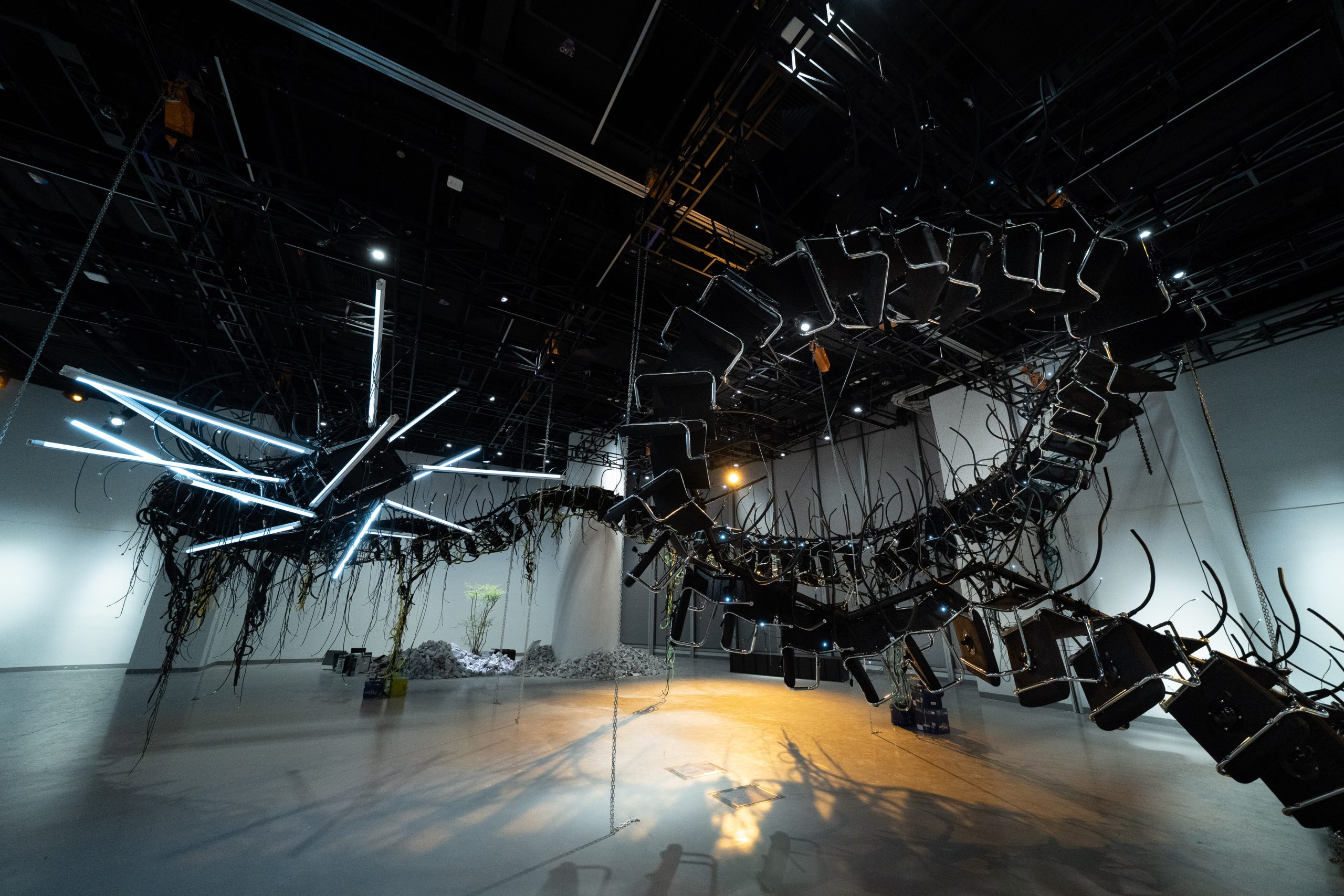 以辦公椅改裝而成、長達42米的大型動態雕塑《我們小心養大的獸》，猶如懸吊在展場中央的機械異獸。PHOTO / HKADC